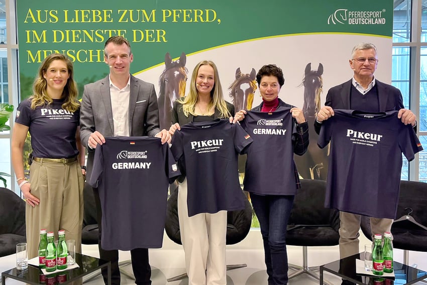 FN-Kommunikationsleiterin Sabine Gregg (v. l.), FN-Vorstandsvorsitzender Dr. Dennis Peiler, Dressurreiterin Katharina Hemmer, Bundestrainerin Monica Theodorescu und Bundestrainer Otto Becker präsentieren die Fan-Shirts für die WM 2026. Foto (c): FN